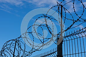 Barbed wire fence on background with blue sky and white clouds. Concept