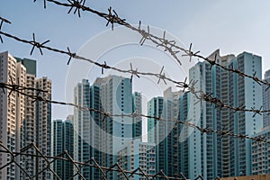 Barbed wire fence closeup with buildings in background