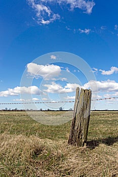 A barbed wire fence with old rustic wooden post