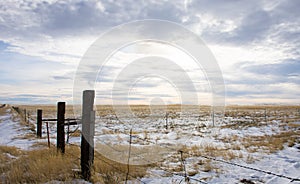 Barbed Wire Fence and Prairie with cloudy skies above.