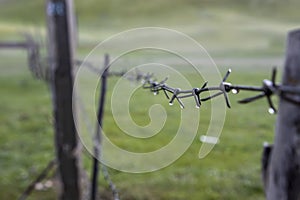 Barbed wire fence with raindrops on a blurred background