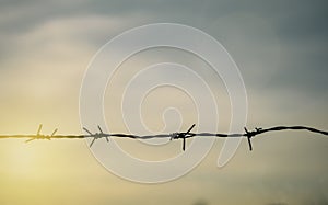 Barbed wire fence with sunset Twilight sky. Chain with spike for safety and security boundary concept for human rights slave,