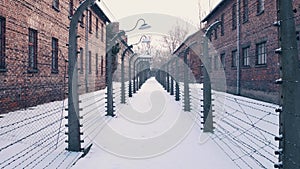 Between barbed wire fences. Auschwitz Birkenau, German Nazi concentration and extermination camp. Barracks in falling