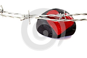 Barbed wire in front of a black stone with a painted red heart isolated on white background