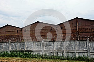 Barbed wire on a gray concrete fence along iron buildings