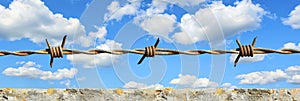 Barbed wire installation enhances security on top of a solid concrete fence wall photo