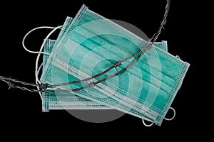 Barbed wire laying on medical mask. Concept of quarantine or epidemic zone or pandemic prevention isolated on black background