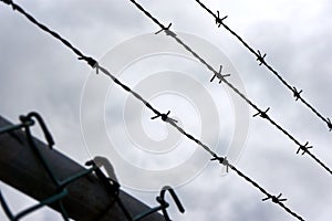 Barbed wire lines and fence against a dramatic dark cloudy