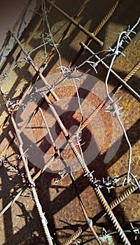 Barbed wire on metal reinforcement on a background of rusty iron.