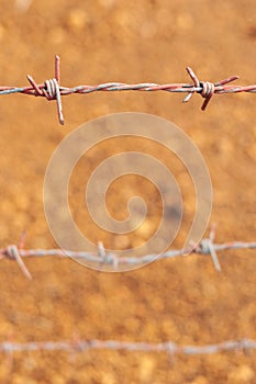 Barbed wire with orange dirt background