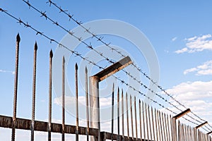 Barbed wire prison fence against the blue sky