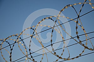 Razor barbed wire on a fence against the sky rolled into circles and spirals protects objects and borders stop intruders and photo