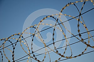 Razor barbed wire on a fence against the sky rolled into circles and spirals protects objects and borders stop intruders  thieves photo