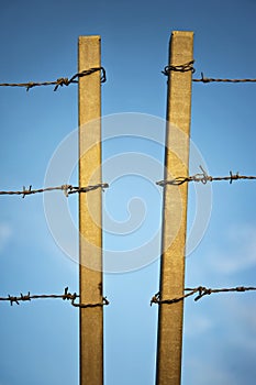 Barbed wire with two concrete columns on blue sky backround