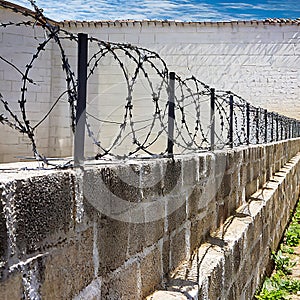 Barbed wire on the wall of the building. Prison fence. AI-generated image