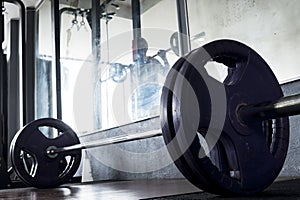 A barbell with 4 rubberized plates readied for a deadlift workout at the gym.