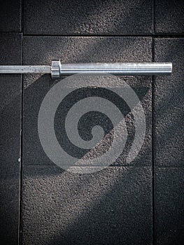 A barbell on an exercise mat with diagonal shadows