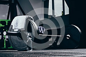 Barbell, towel and bottle of water on floor