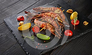 Barbeque grilled prawns with spicy ingredients garlic and tomato on dark wooden table