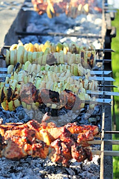 Barbeque meat and vegetable skewers cooked on fire in very long cafe grill outdoors, BBQ