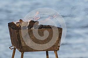 Barbeque by the sea. Coals burn beautifully in the old grill, orange flame flutters