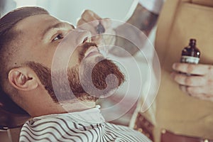 The barber applies the beard oil with a dropper