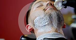 Barber applying shaving cream on client beard 4k