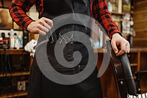 Barber in apron with cutting tools, barbershop