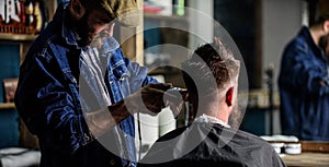 Barber with clipper trimming hair of client, rear view. Hipster client getting haircut. Hipster lifestyle concept
