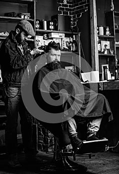 Barber with clipper trimming hair on nape of client. Hipster client getting haircut. Barber with hair clipper works on