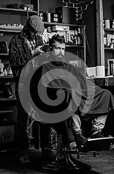 Barber with clipper trimming hair on nape of client. Hipster client getting haircut. Hipster hairstyle concept. Barber