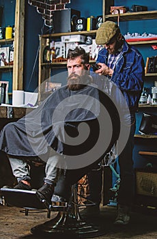 Barber with clipper trimming hair on nape of client. Hipster client getting haircut. Hipster hairstyle concept. Barber