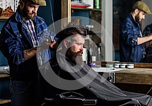 Barber with clipper trimming hair on nape of client. Hipster client getting haircut. Hipster lifestyle concept. Barber