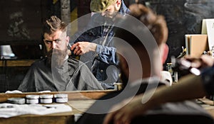 Barber with clipper trimming hair on nape of client. Hipster hairstyle concept. Hipster client getting haircut