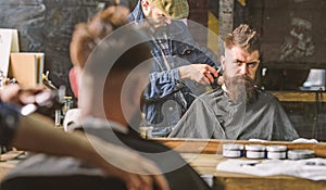 Barber with clipper trimming hair on nape of client. Hipster hairstyle concept. Hipster client getting haircut