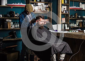 Barber with clipper trimming hair on nape of client. Hipster style concept. Hipster client getting haircut. Barber with