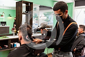 Barber combs and dries the hair of a customer in a barber shop