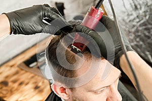 Barber cut hair and shaves the parting adult man on a brick wall background. Close up portrait of a guy