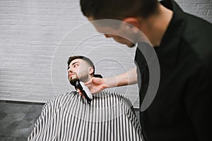 Barber cuts the barber shop`s beard clipper. Man deals with the correction of the beard in the men`s shop. Hairdresser does a
