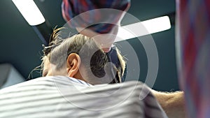 Barber cuts the boy`s hair. The process of forming a haircut close-up.