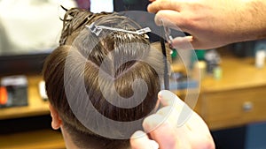 Barber cuts the boy`s hair. The process of forming a haircut close-up.