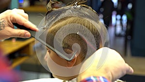 Barber cuts the boy`s hair. The process of forming a haircut close-up.