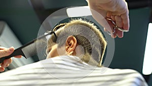 Barber cuts the boy`s hair. The process of forming a haircut close-up.