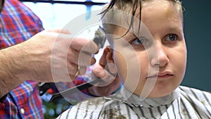 Barber cuts the boy`s hair. The process of forming a haircut close-up.