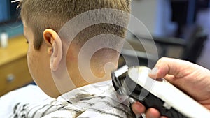 Barber cuts the boy`s hair. The process of forming a haircut close-up.