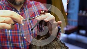 Barber cuts the boy`s hair. The process of forming a haircut close-up.