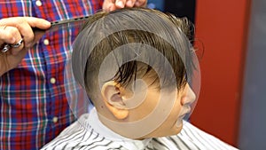 Barber cuts the boy`s hair. The process of forming a haircut close-up.