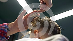 Barber cuts the boy`s hair. The process of forming a haircut close-up.