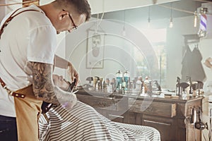 Barber cuts the client`s beard in his barber shop