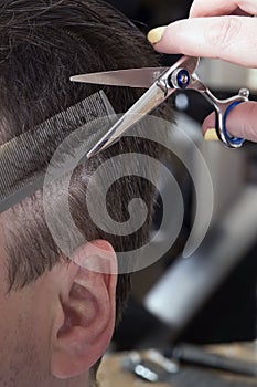 Barber cuts hair of handsome satisfied client.